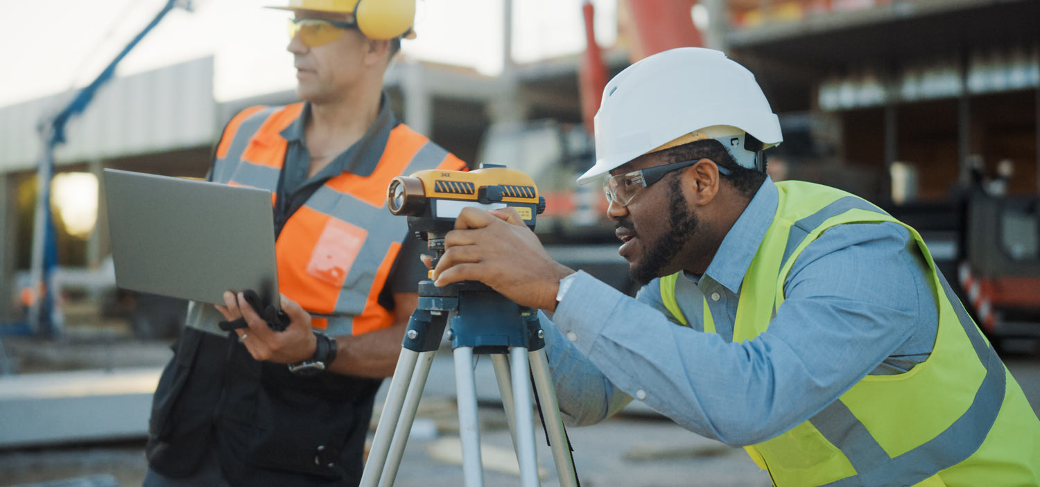 two construction workers using surveying equipment