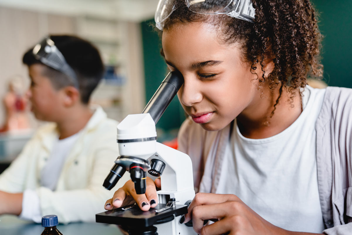 young girl using microscope