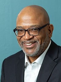 Patrick Duggan with glasses smiling at the camera