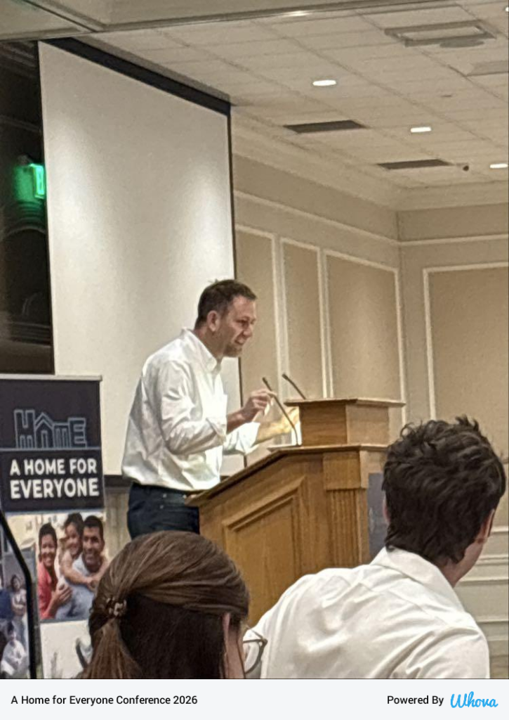 Brian Goldstone giving keynote speech behind a lectern at the conference